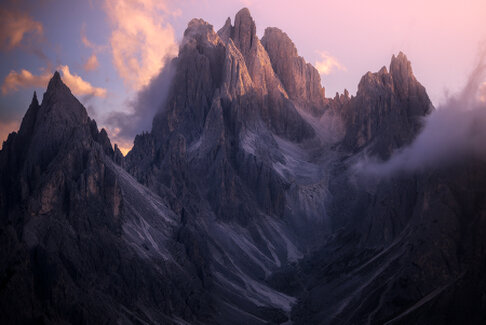 Le cime frastagliate dei Cadini di Misurina emergono tra le nuvole illuminate dalla luce del tramonto. La nebbia avvolge progressivamente la montagna, lasciando visibili solo per pochi istanti le sue forme maestose in un